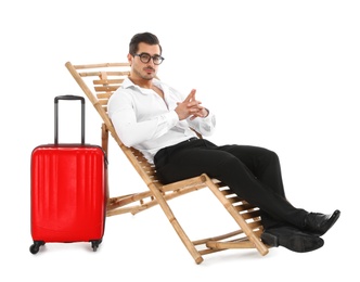 Photo of Young businessman with suitcase on sun lounger against white background. Beach accessories