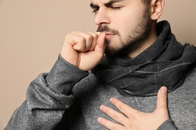 Photo of Handsome young man coughing against color background