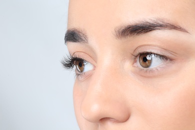 Young woman with beautiful eyelashes on gray background, closeup view