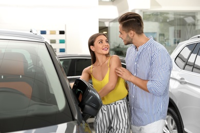 Photo of Young couple choosing new car in salon