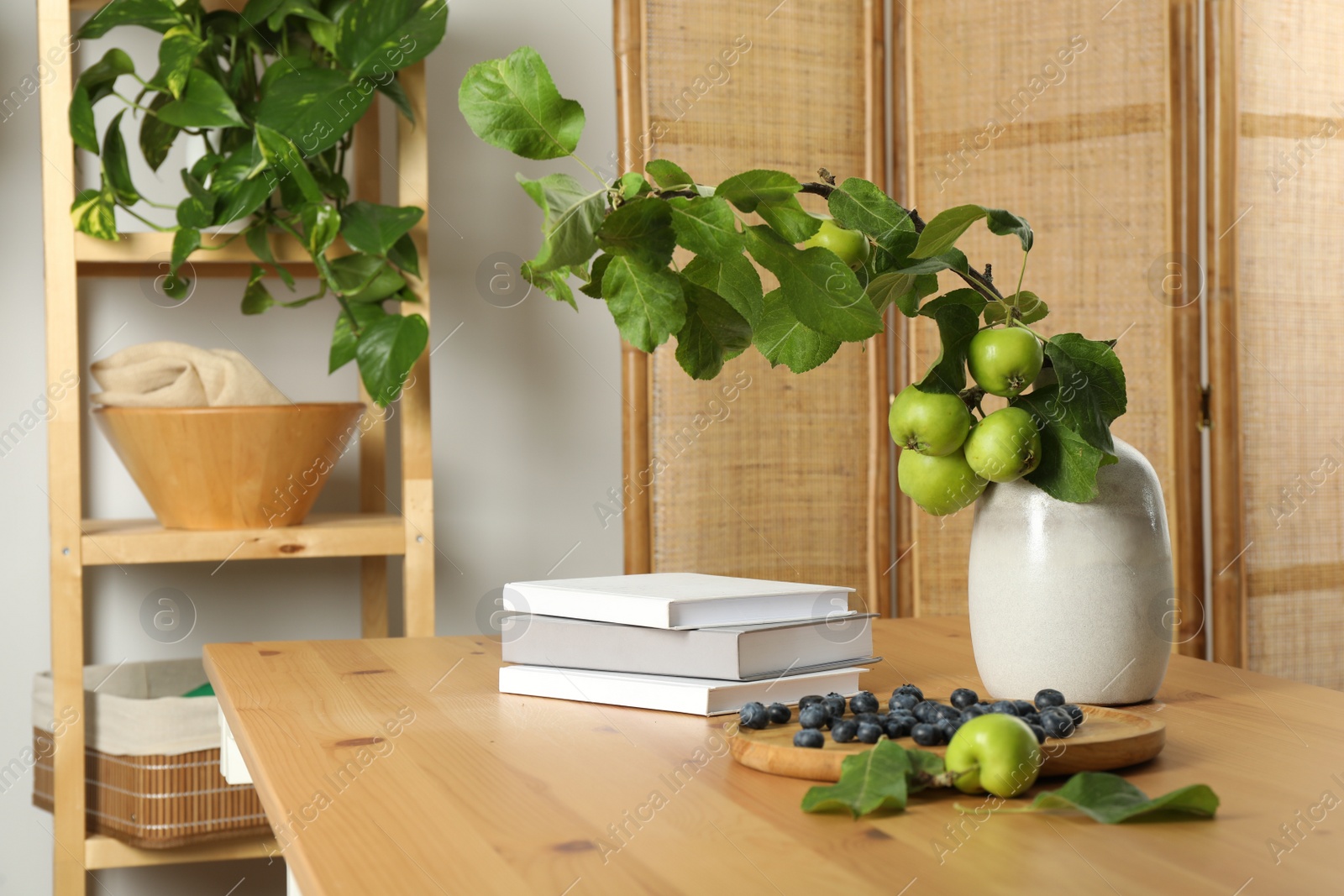 Photo of Books, blueberries and branch with green apples on wooden table in room