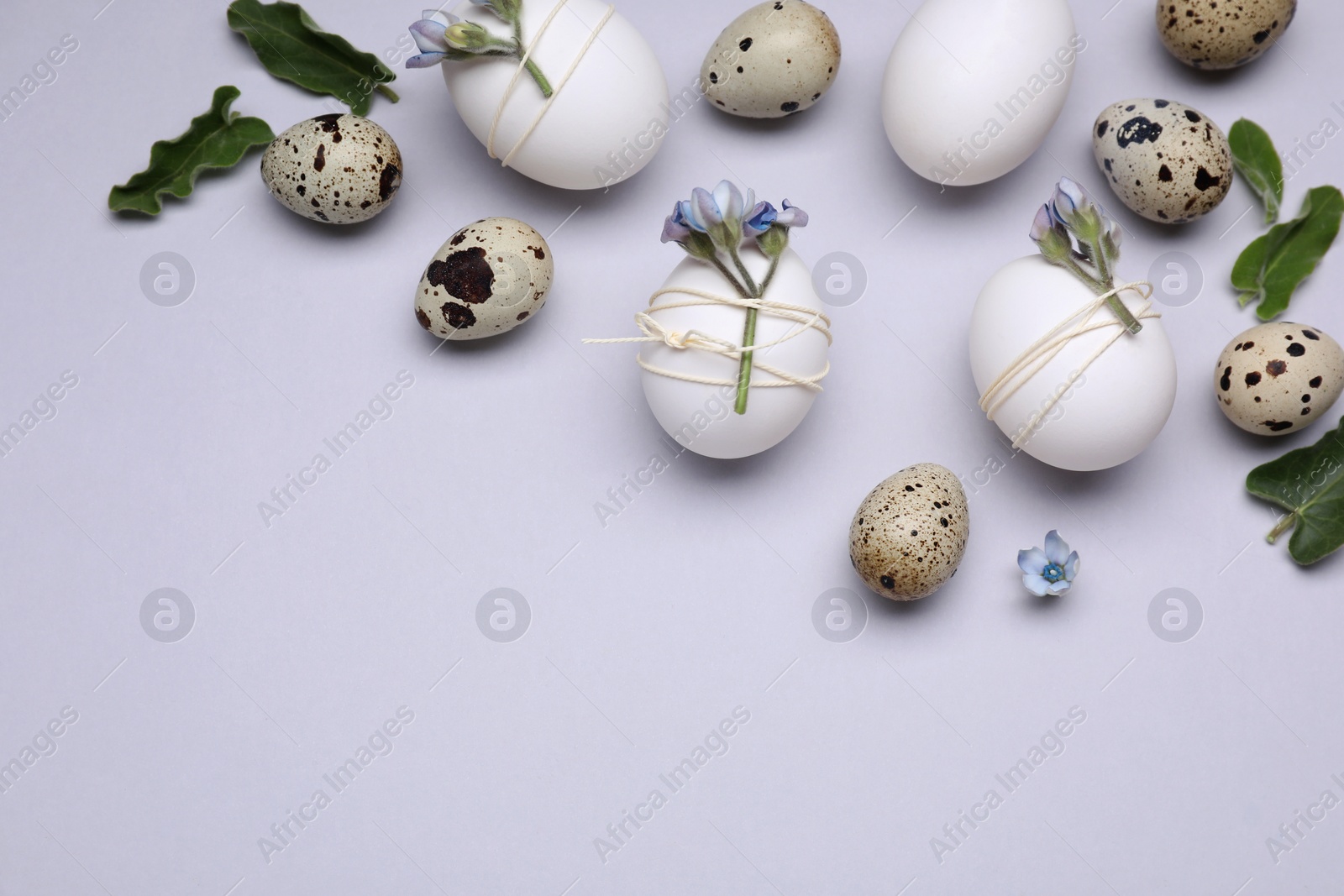 Photo of Beautifully decorated Easter eggs on light grey background, flat lay. Space for text