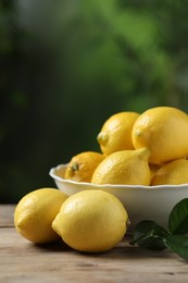 Fresh lemons and green leaves on wooden table