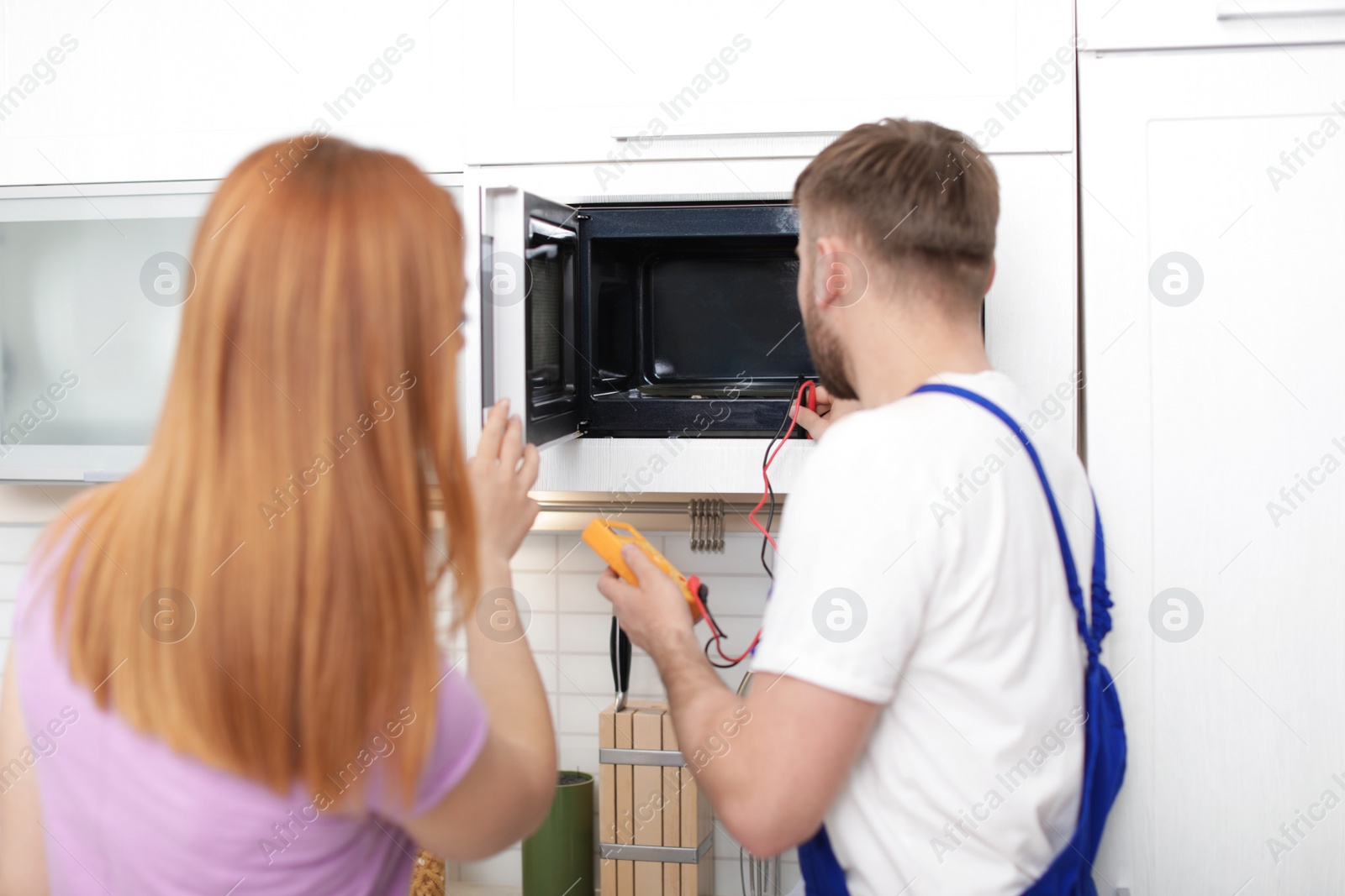 Photo of Housewife and repairman near microwave oven in kitchen