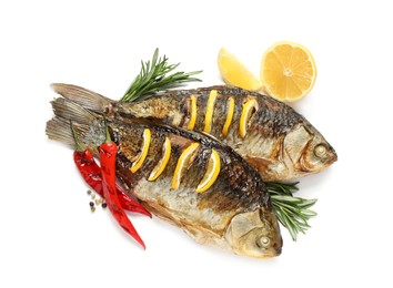 Photo of Tasty homemade roasted crucian carps with rosemary, lemon and chili peppers on white background, top view. River fish