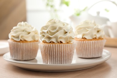 Photo of Tasty cupcakes with vanilla cream on light wooden table, closeup