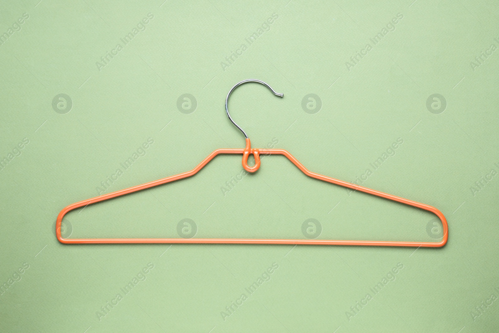 Photo of Empty orange hanger on olive color background, top view