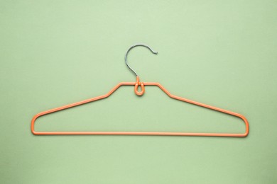 Photo of Empty orange hanger on olive color background, top view