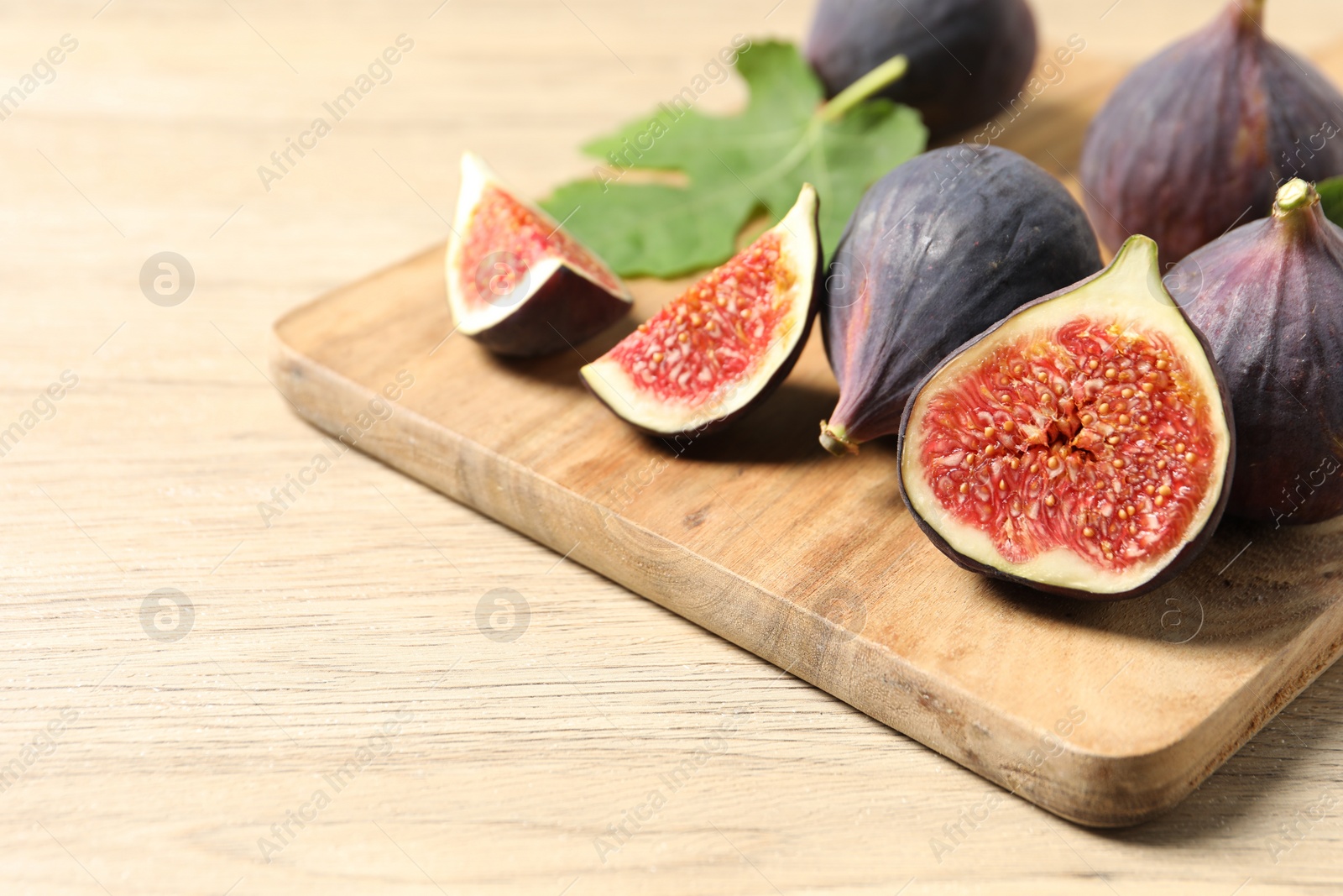 Photo of Whole and cut ripe figs on wooden table, closeup. Space for text