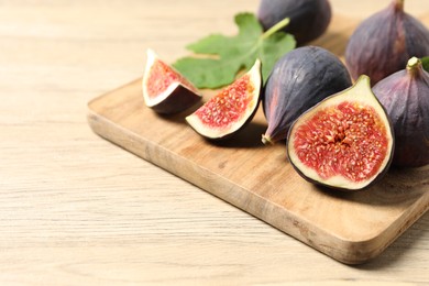 Whole and cut ripe figs on wooden table, closeup. Space for text