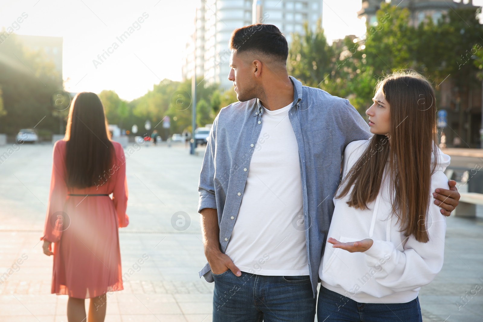 Photo of Disloyal man looking at another woman while walking with his girlfriend outdoors