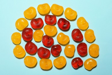 Delicious gummy cherry candies on light blue background, flat lay