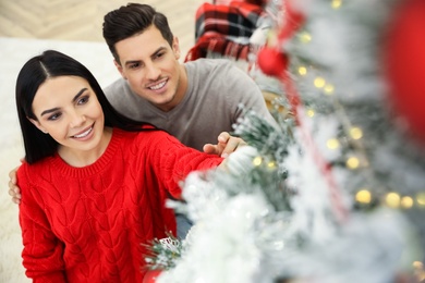 Happy couple decorating Christmas tree at home