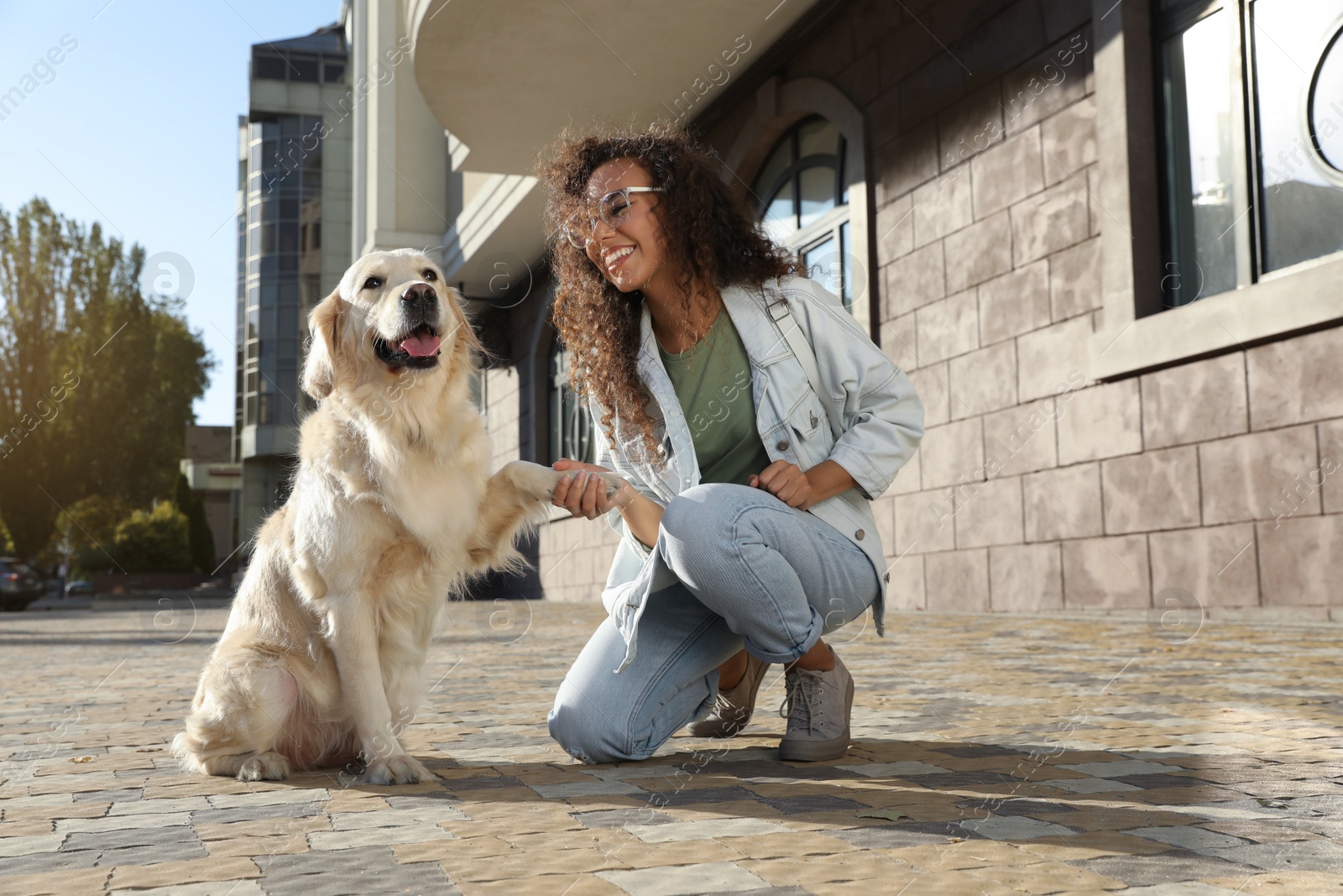 Photo of Young African-American woman and her Golden Retriever dog outdoors