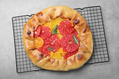 Photo of Tasty galette with citrus fruits and rosemary on grey table, top view