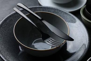 Set of clean tableware on black table, closeup