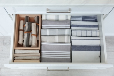 Photo of Open drawer with folded napkins and towels indoors. Order in kitchen