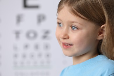 Cute little girl against vision test chart, closeup