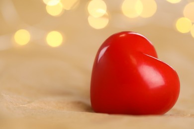 Red heart on kraft paper against festive lights, space for text. St. Valentine's day