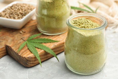 Photo of Composition with jars of hemp protein powder on light table