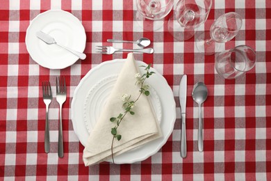 Stylish setting with cutlery, plates, napkin, glasses and floral decor on table, flat lay