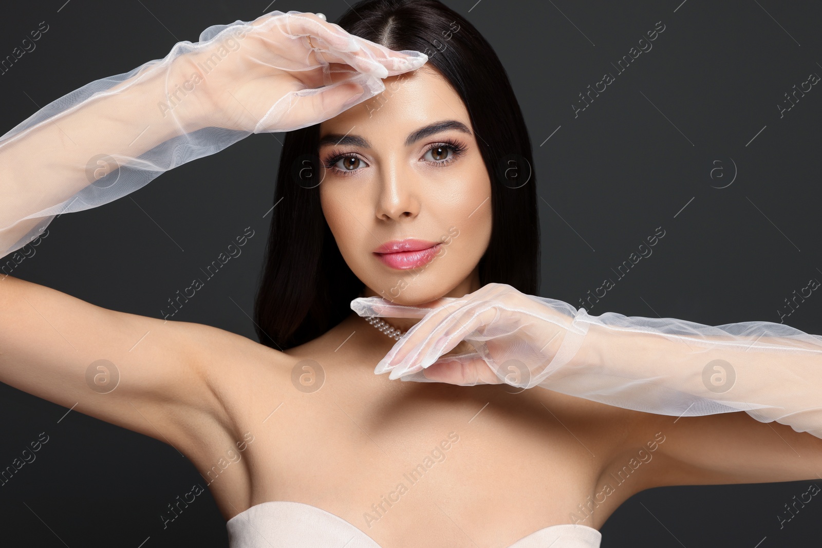 Photo of Portrait of beautiful young woman in evening gloves on black background
