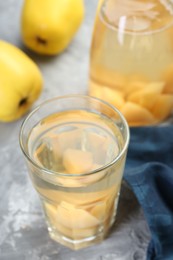 Photo of Delicious quince drink and fresh fruits on grey table, closeup