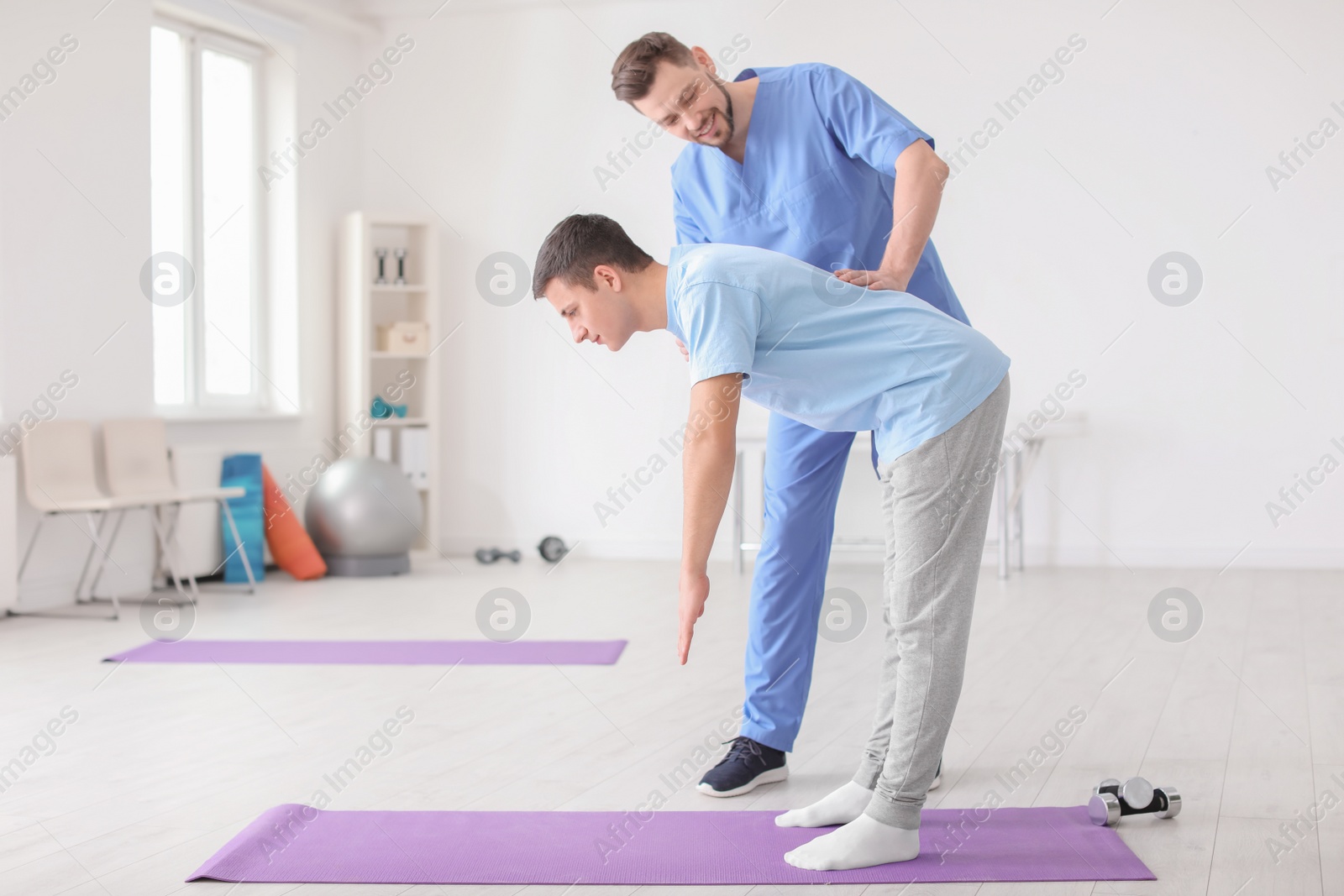 Photo of Physiotherapist working with male patient in clinic