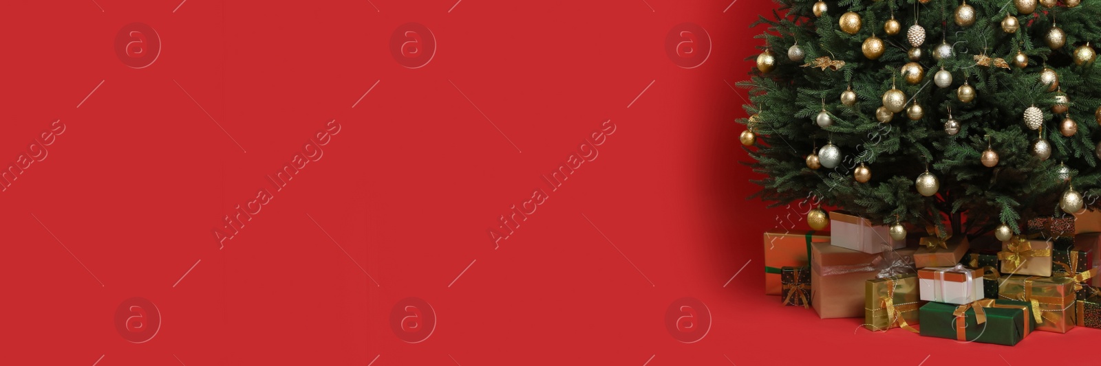 Image of Beautifully decorated Christmas tree and gift boxes on red background, space for text. Banner design