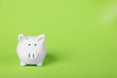 Photo of Ceramic piggy bank on light green background, space for text. Financial savings