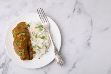 Photo of Delicious rice and chicken with curry sauce on white marble table, top view. Space for text