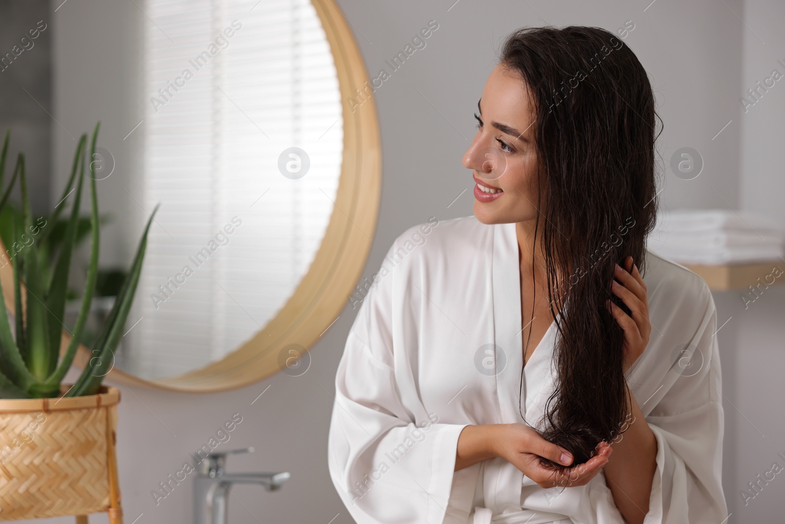 Photo of Young woman applying cosmetic hair mask in bathroom. Space for text