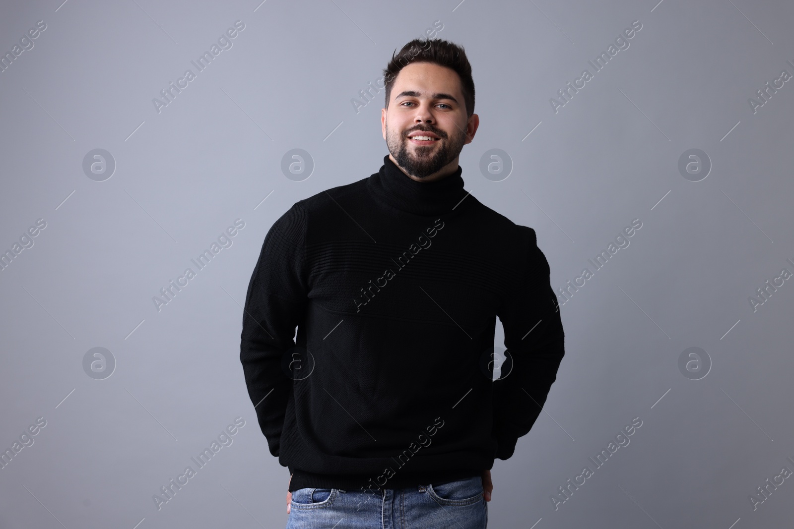 Photo of Happy man in stylish black sweater on grey background