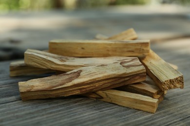 Palo santo sticks on wooden table outdoors, closeup