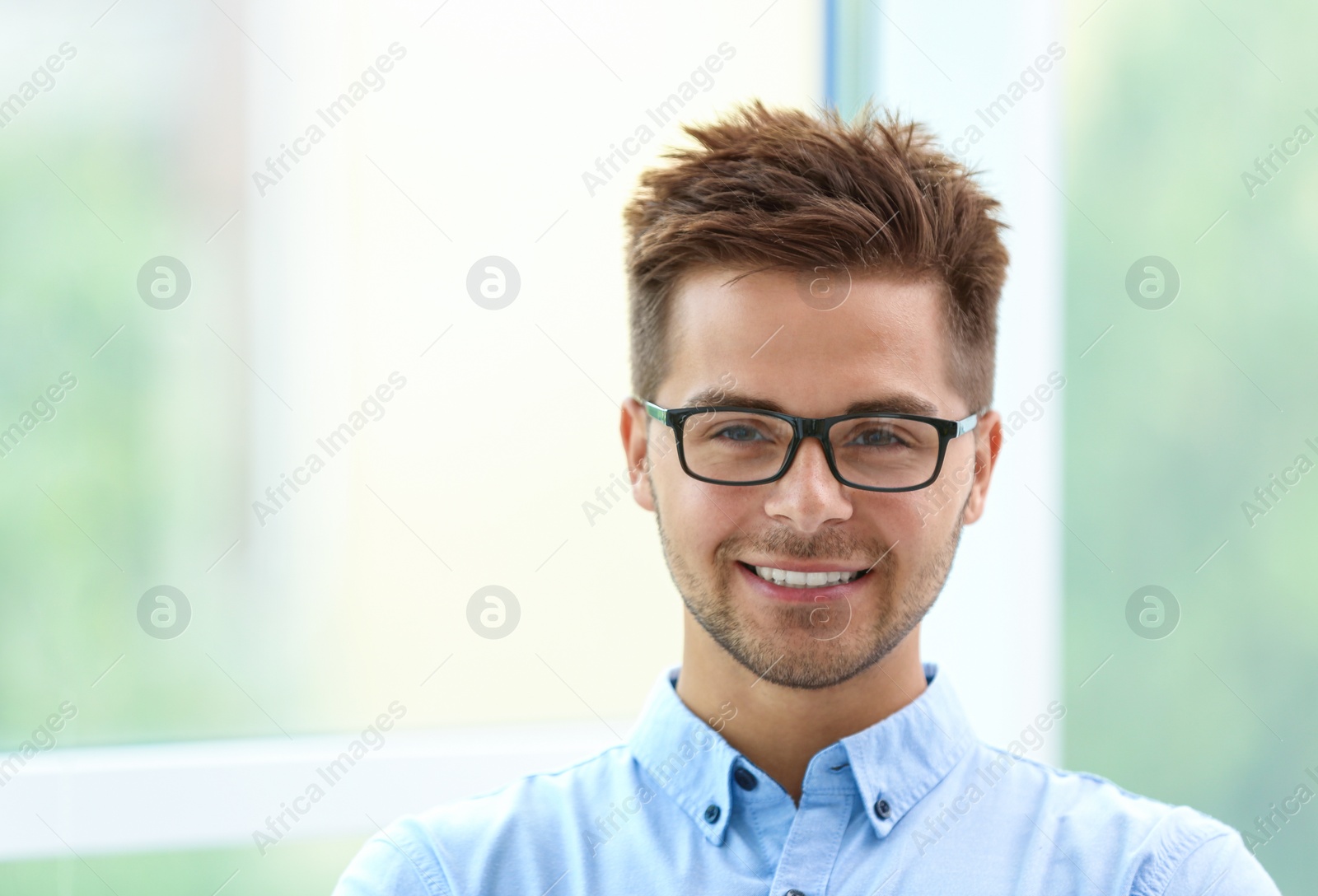 Photo of Portrait of handsome young man with glasses near window