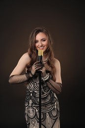 Photo of Beautiful young woman in stylish dress with microphone singing on dark background