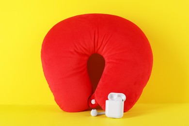 Photo of Red travel pillow and earphones on yellow background