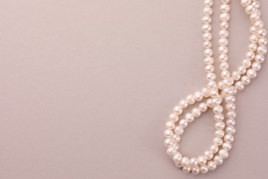 Photo of Elegant pearl necklace on beige background, top view. Space for text