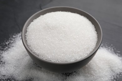 Granulated sugar on black table, closeup view