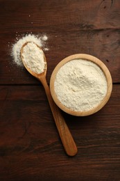 Photo of Baking powder in bowl and spoon on wooden table, top view