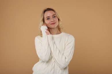 Photo of Beautiful woman in stylish warm sweater on beige background