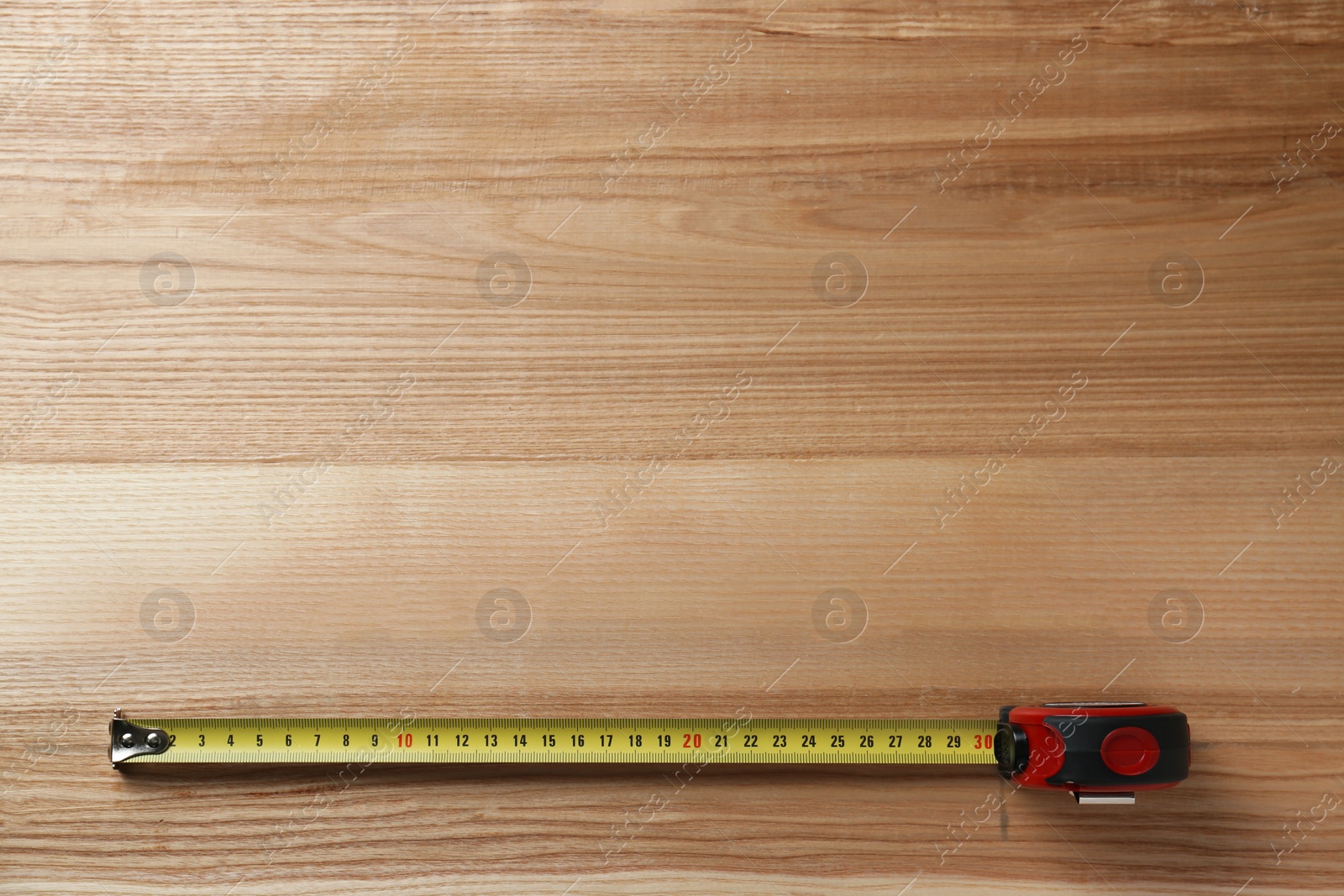 Photo of Tape measure on wooden background, top view. Space for text