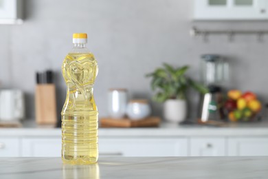 Photo of Bottle of cooking oil on white marble table in kitchen. Space for text