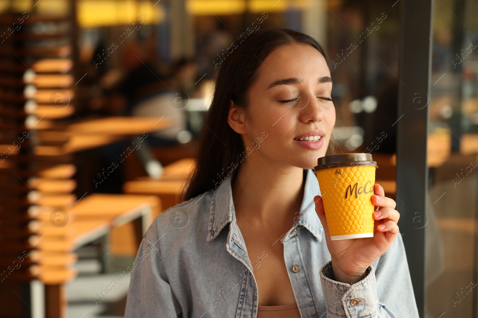 Photo of Lviv, Ukraine - September 26, 2023: Woman with hot McDonald's drink in cafe, space for text