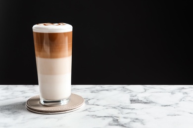 Photo of Glass with delicious caramel latte on table