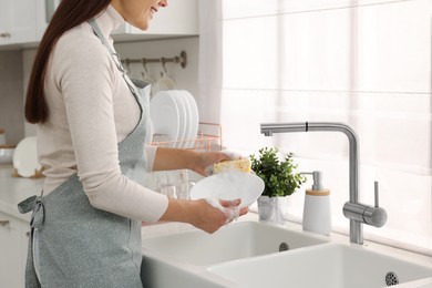 Photo of Woman washing bowl at sink in kitchen, closeup