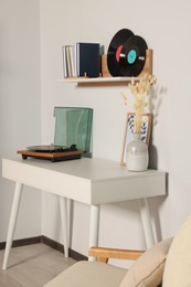 Photo of Room interior with stylish turntable on white table and vinyl records
