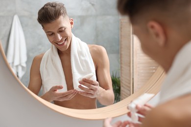 Photo of Handsome man with moisturizing cream in bathroom