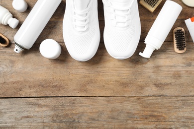 Flat lay composition with stylish footwear and shoe care accessories on wooden background, space for text