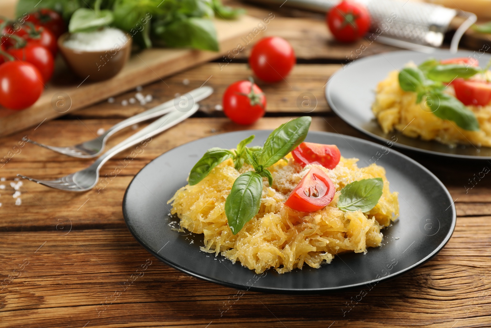 Photo of Tasty spaghetti squash with tomatoes and basil served on wooden table